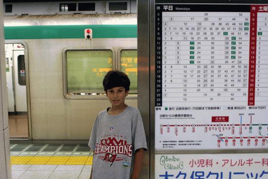 Paul stands next to the subway schedule in Osaka.