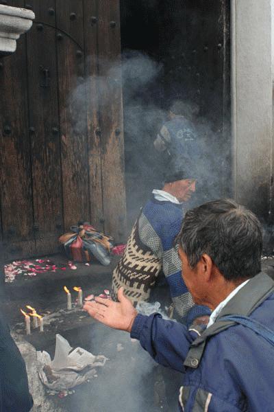 Mayan men light incense and say prayers before the catholic mass.  Tourists are not allowed through the sacred front door. Iglesia Santos Tomas was built in 1532.