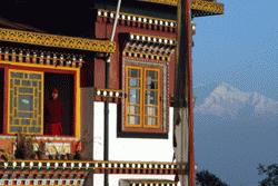 A Buddist monk peers out the window on a beautiful morning in Darjeeling with Kanchenjunga in the background