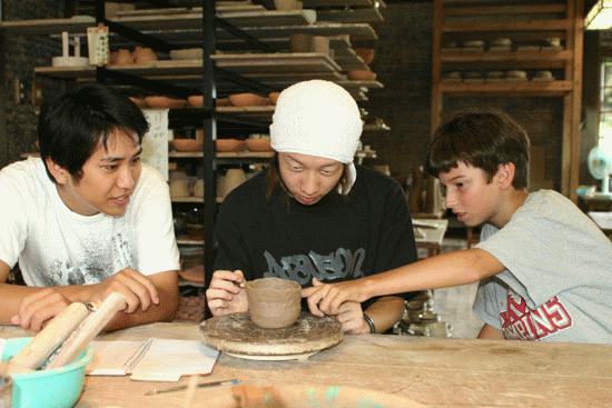 Kazu and Yuta work with Paul during a pottery lesson.