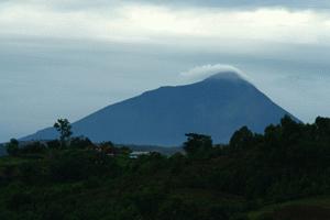 A volcanoe, home to mountain gorillas in Rwanda, looms over Lake Bunyoni