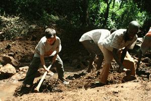 Paul digs up a large section of earth to clear the path for water coming out of the spring.