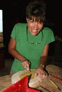 Therese carves a jack fruit cutting board. These boards will be auctioned off at the first anniversary fundraiser.