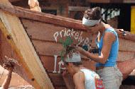 Volunteers paint the insignia of the club or person who donated the making of the boat.